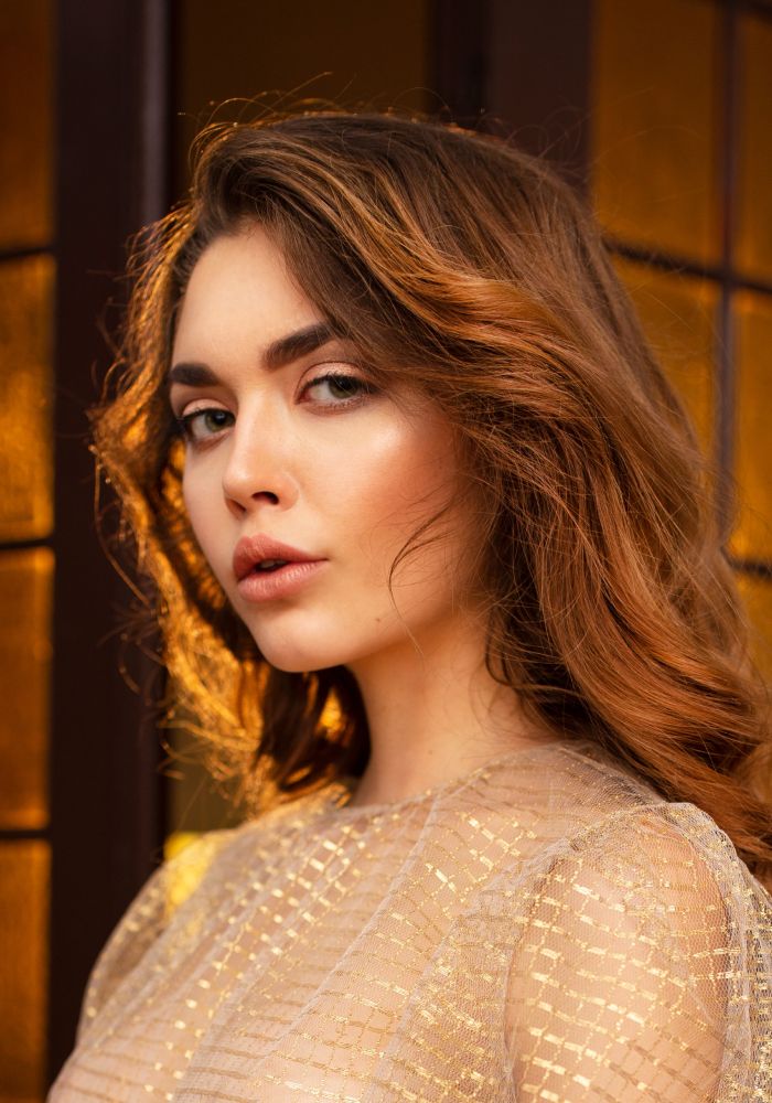 Woman with wavy hair in soft golden light.